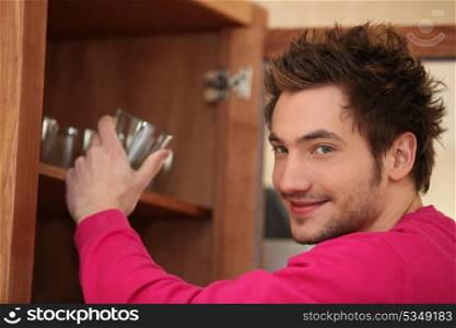 Man getting a glass out of the cupboard