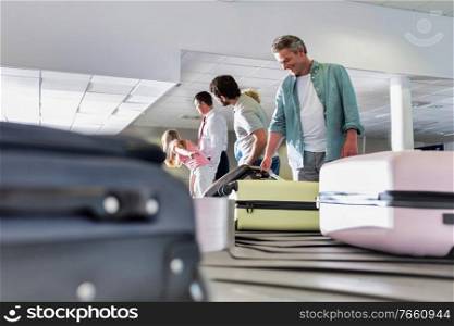 Man getting his suitcase on baggage claiming area in airport