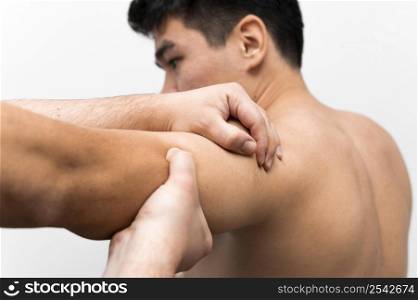 man getting shoulder pain massage from physiotherapist