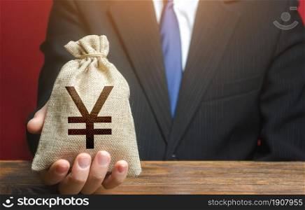 Man gives a chinese yuan or japanese yen money bag. Loan issuance. Financial support, leasing. Earnings and profits. Investments, financing Lobbying. Accounting and accounting, tax payment. Funding