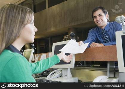 Man giving a document to female customer service representative