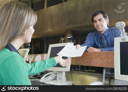 Man giving a document to female customer service representative