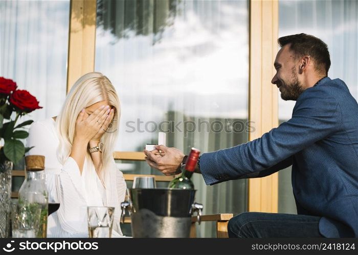 man giving engagement ring her shy girlfriend