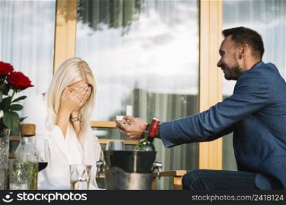 man giving engagement ring her shy girlfriend