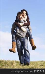 Man Giving His Wife A Piggy Back Ride In Park