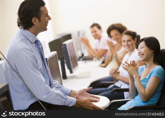Man giving lecture in applauding computer class