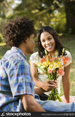 Man giving smiling woman bouquet of flowers.