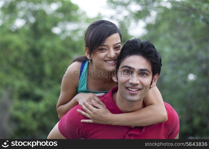 Man giving woman piggy back ride in park