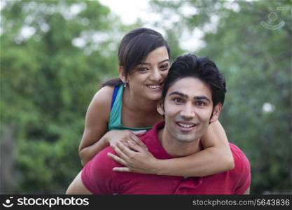 Man giving woman piggy back ride in park