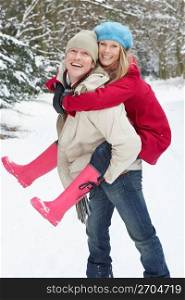 Man Giving Woman Piggyback In Snowy Woodland