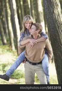 Man Giving Woman Piggyback On Country Walk