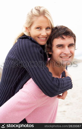 Man Giving Woman Piggyback On Winter Beach