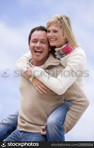 man giving woman piggyback ride outdoors smiling