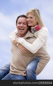 man giving woman piggyback ride outdoors smiling