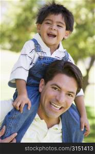 Man giving young boy shoulder ride outdoors smiling