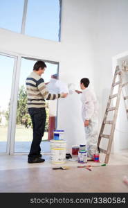 Man going through house plan while painter painting the wall