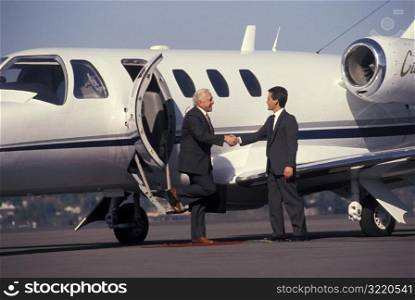 Man Greeting Businessman Stepping Off Plane