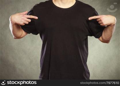 Man guy in blank shirt with copy space pointing.. Fashionable casual man in black blank shirt with empty copy space pointing at himself. Guy in studio on black. Fashion advertisement.