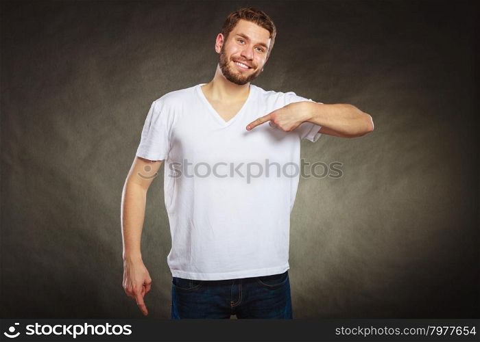 Man guy in blank shirt with copy space pointing.. Portrait of happy handsome fashionable casual man in white blank shirt with empty copy space pointing at himself. Young guy in studio on black. Fashion advertisement.