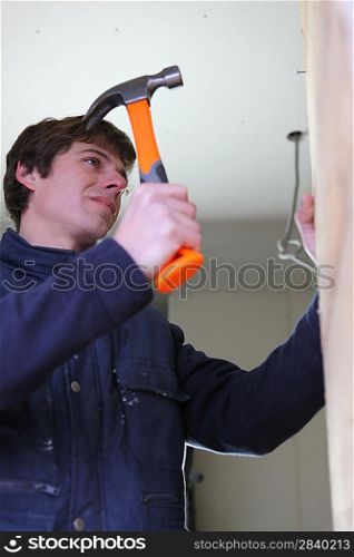 Man hammering a wall