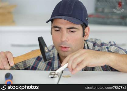 man hammering a wooden cabinet