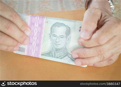 Man hand counting Thai baht banknote, stock photo