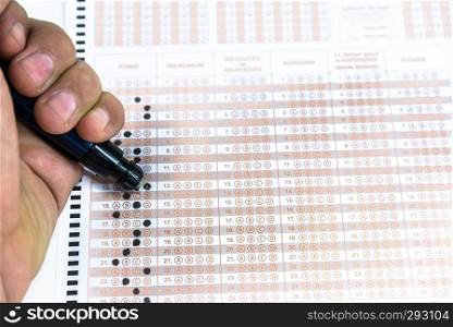 Man hand Erasing answer with pencil on Test score sheet with answers.. Erasing answer with pencil on Test score sheet 