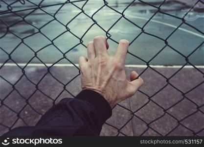 man hand grabbing a metallic fence