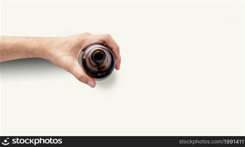 Man hand holding a bottle of beer top up view in a light white background with copy space