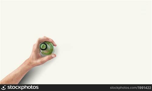 Man hand holding a bottle of beer top up view in a light white background with copy space