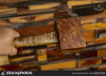 Man hand holding a mallet hammer made of burl wood tools for used by carpenter in workshop on isolated blurred blackground