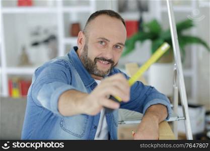 man hand holding a tape measure in home