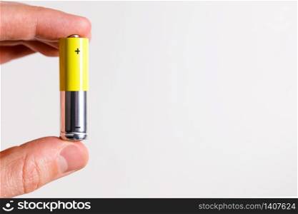 Man hand holding alkaline battery AA size, close up, isolated on white background with copy space.