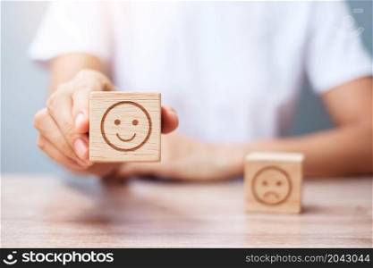 Man hand holding emotion face block. Customer choose Emoticon for user reviews. Service rating, ranking, customer review, satisfaction, evaluation and feedback concept
