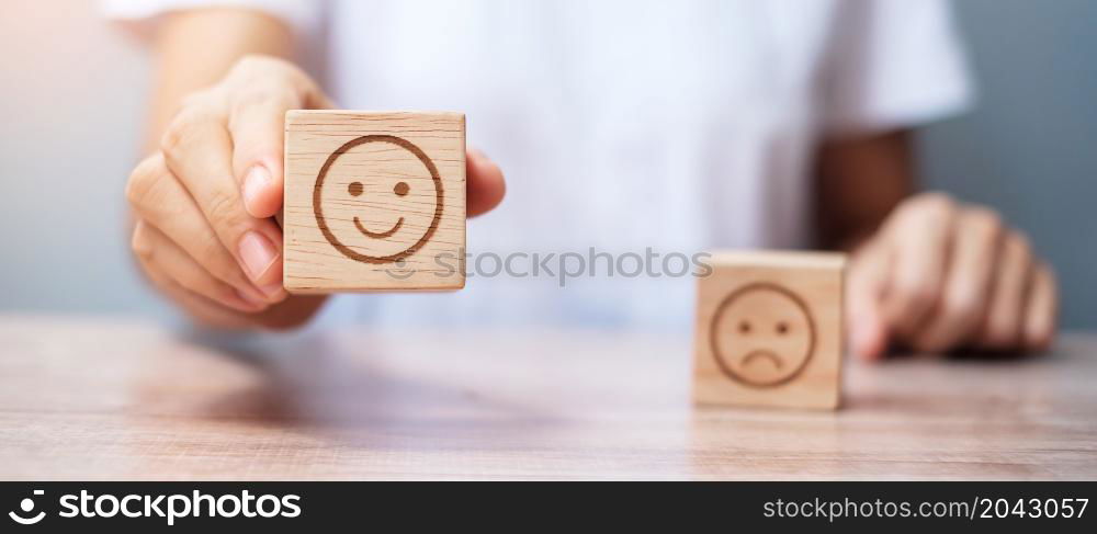 Man hand holding emotion face block. Customer choose Emoticon for user reviews. Service rating, ranking, customer review, satisfaction, evaluation and feedback concept