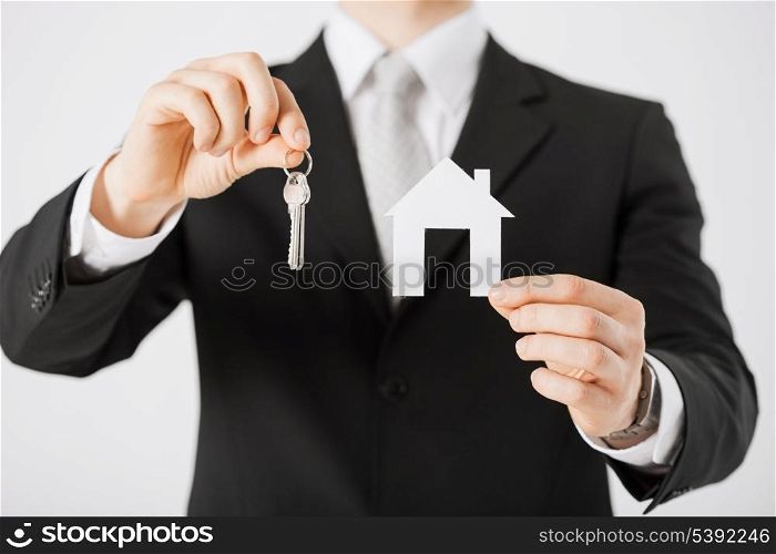 man hand holding house keys and paper house