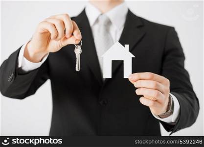 man hand holding house keys and paper house
