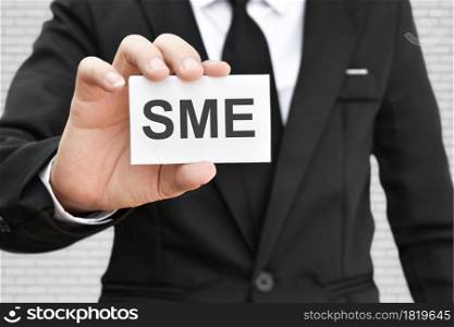 Man hand holding paper card with word SME. Concept of small and medium-sized enterprises business.