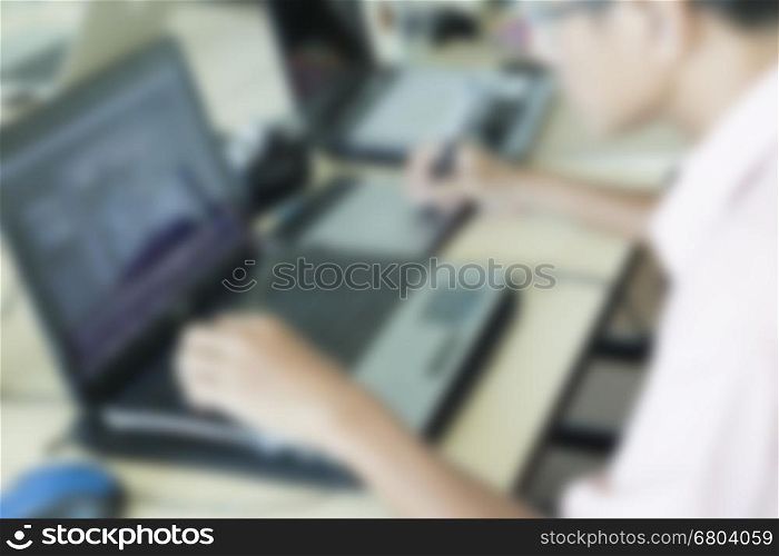 man' hand holding pen working on digital tablet and computer notebook for graphic design work, blur and vintage tone