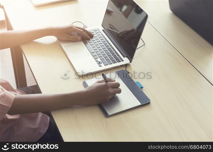 man' hand holding pen working on digital tablet and computer notebook for graphic design work, vintage tone