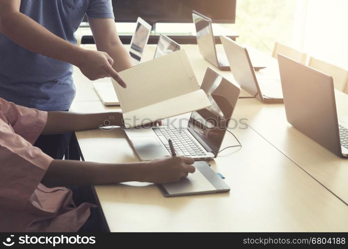 man' hand holding pen working on digital tablet and computer notebook for graphic design work, vintage tone