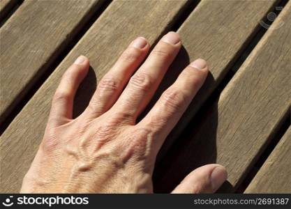 man hand over sunny teak tropical wood lines horizontal image