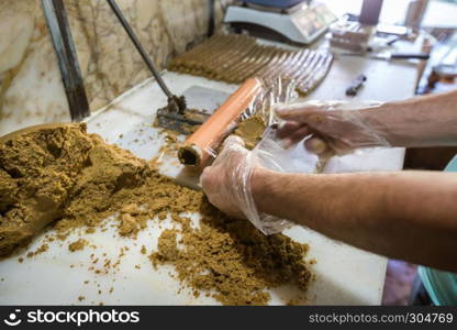 Man hand prepares traditional Lok or Tatuni dessert.Lok dessert made by mixing dried mulberries floor and walnut and then mashing for3 hours. Kemaliye,Turkey.. Traditional Lok or Tatuni dessert in Kemaliye,Turkey