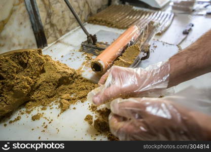 Man hand prepares traditional Lok or Tatuni dessert.Lok dessert made by mixing dried mulberries floor and walnut and then mashing for3 hours. Kemaliye,Turkey.. Traditional Lok or Tatuni dessert in Kemaliye,Turkey