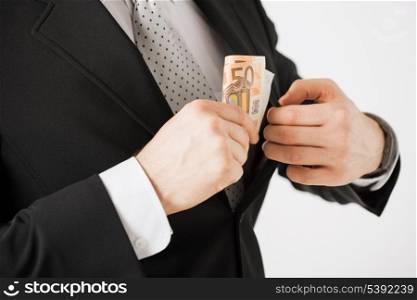 man hand putting euro cash money into suit pocket