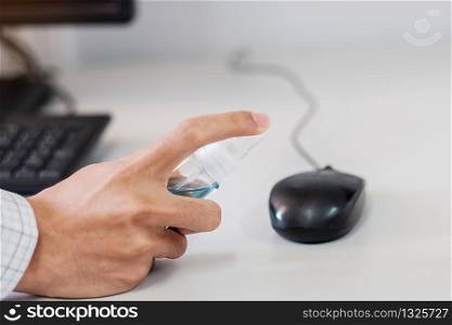 Man hand spraying alcohol sanitizer bottle to the Mouse and Keyboard of Computer, against Novel coronavirus or Corona Virus Disease (Covid-19) at office or home. Antiseptic, Hygiene and Health concept