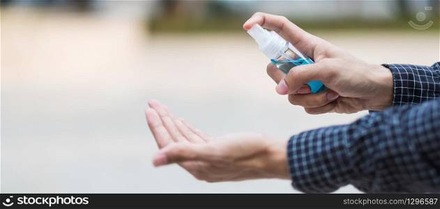 man hand spraying hand alcohol sanitizer bottle dispenser, against Novel coronavirus or Corona Virus Disease (Covid-19) at public outdoor. Antiseptic, Hygiene and Healthcare concept