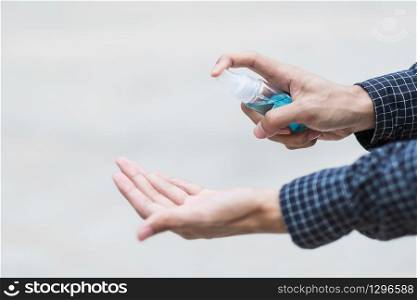 man hand spraying hand alcohol sanitizer bottle dispenser, against Novel coronavirus or Corona Virus Disease (Covid-19) at public outdoor. Antiseptic, Hygiene and Healthcare concept