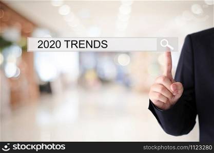 Man hand touching 2020 trends on search bar over blur office background, success in business concept, seo