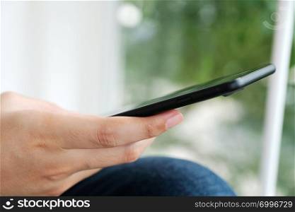 Man hand using black smart phone over blur background, technology and lifestyle
